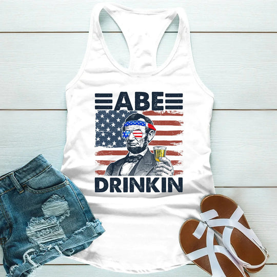 White tank top with American flag graphic and Abraham Lincoln holding a drink, patriotic summer tee