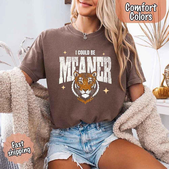 May include a vintage-style Comfort Colors t-shirt featuring a bold tiger graphic and “I Could Be Meaner” text, laid flat on a neutral background.