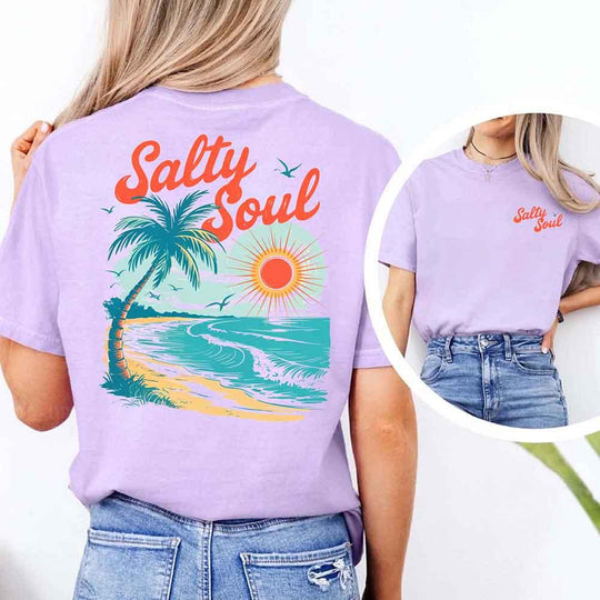 May include a short-sleeve t-shirt with “Salty Soul” printed in bold script on the front left chest and a large back graphic featuring a tropical beach scene with a palm tree, ocean waves, a bright orange sun, and flying birds.