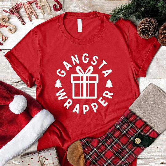 Red Christmas t-shirt with Gangsta Wrapper gift box print, surrounded by holiday decor.