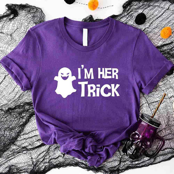 May include matching couple Halloween shirts with bold white text, one reading ‘I’m Her Trick’ with ghost graphic on orange tee, and the other reading ‘I’m His Treat’ with witch silhouette on black tee – funny spooky couple apparel.