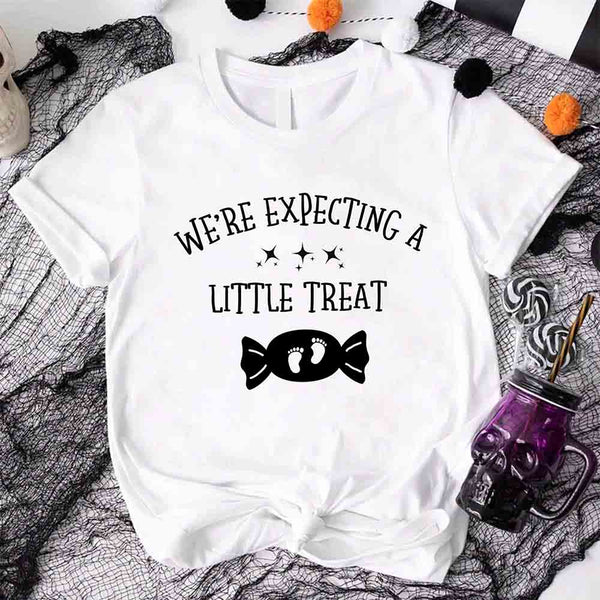 May include matching couple Halloween pregnancy announcement shirts, one reading ‘We’re Expecting a Little Treat’ with candy and baby footprints, and the other reading ‘It’s Not Trick’ with candy graphic – fun maternity reveal apparel.