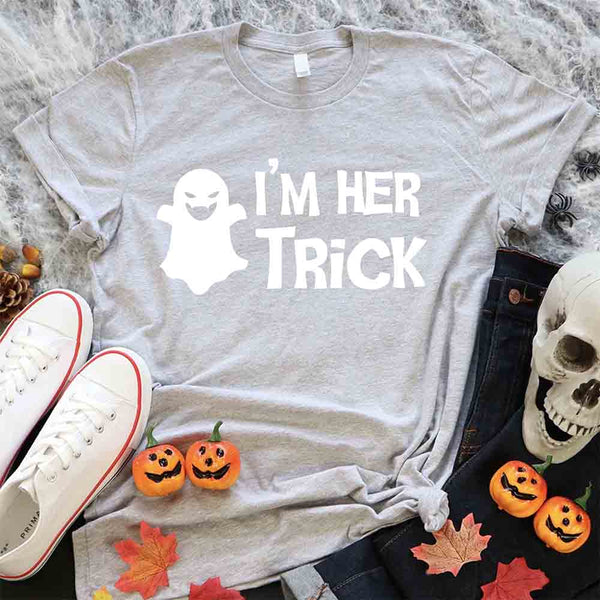 May include matching couple Halloween shirts with bold white text, one reading ‘I’m Her Trick’ with ghost graphic on orange tee, and the other reading ‘I’m His Treat’ with witch silhouette on black tee – funny spooky couple apparel.
