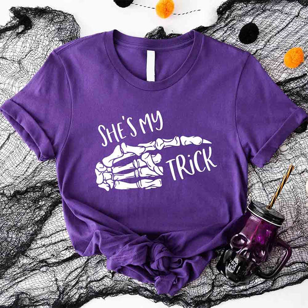 May include matching couple Halloween shirts with skeleton hand graphics, one reading ‘She’s My Trick’ on orange tee and the other reading ‘He’s My Treat’ on black tee – funny spooky couple apparel.