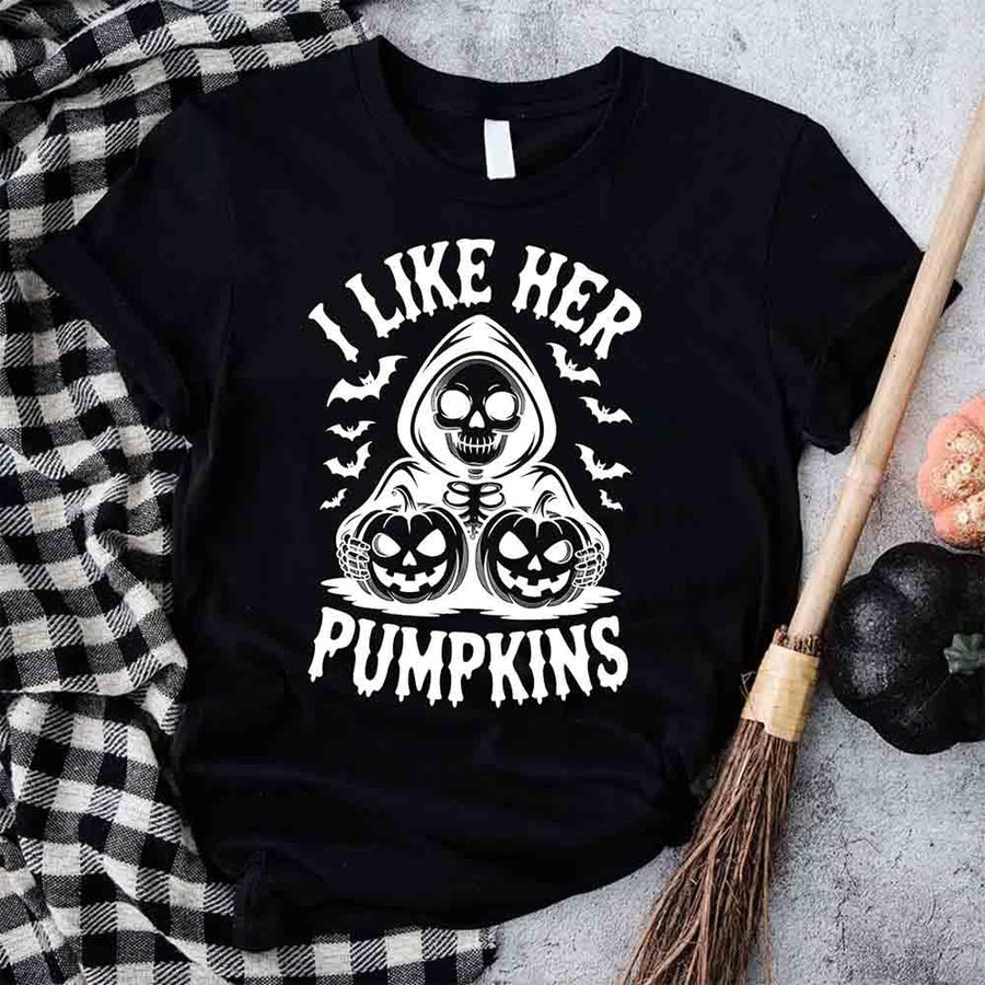 Black t-shirt with Halloween design featuring text 'I Like Her Pumpkins' on a checkered fabric background.