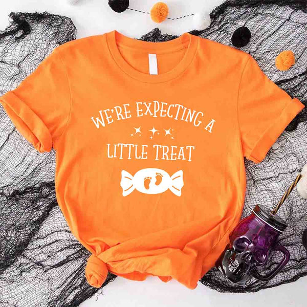 May include matching couple Halloween pregnancy announcement shirts, one reading ‘We’re Expecting a Little Treat’ with candy and baby footprints, and the other reading ‘It’s Not Trick’ with candy graphic – fun maternity reveal apparel.