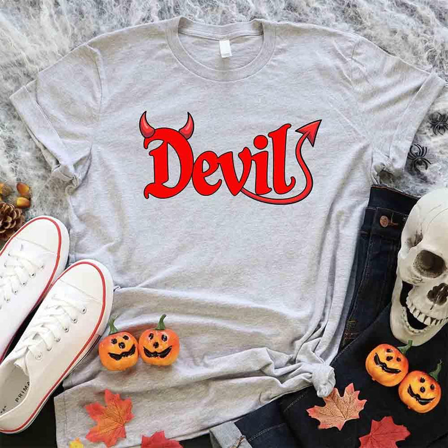 Gray t-shirt with 'Devil' in red text, surrounded by Halloween decorations on a marble surface.
