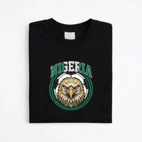 Black Nigeria soccer fan t-shirt with eagle and soccer ball graphic, folded on white background.