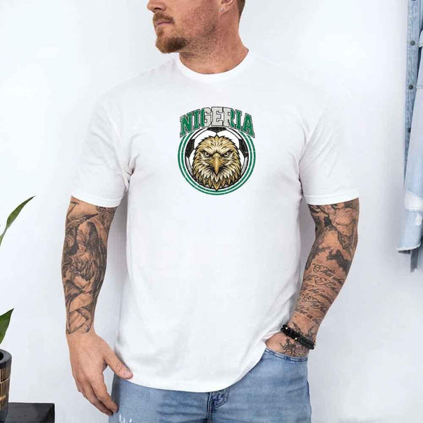 White Nigeria soccer fan t-shirt with eagle graphic and green accents, worn by man with tattoos.