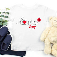 White t-shirt with 'Love Bug' design, navy slippers, and a teddy bear on a white background