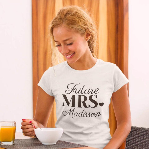 Woman wearing a 'Future Mrs. Madisson' t-shirt, sitting at a table with a glass of orange juice and a bowl.