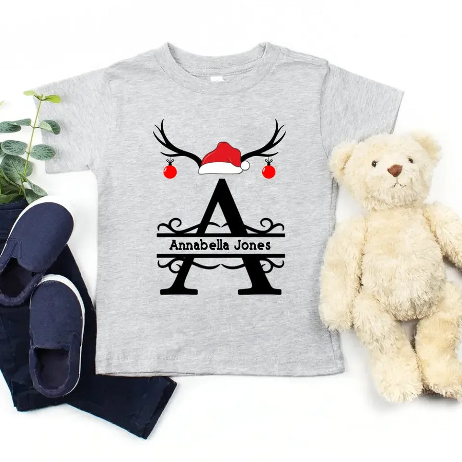 May include a personalized Christmas T-shirt with a single initial printed in a holiday-themed design on the front.