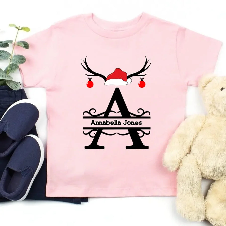May include a personalized Christmas T-shirt with a single initial printed in a holiday-themed design on the front.
