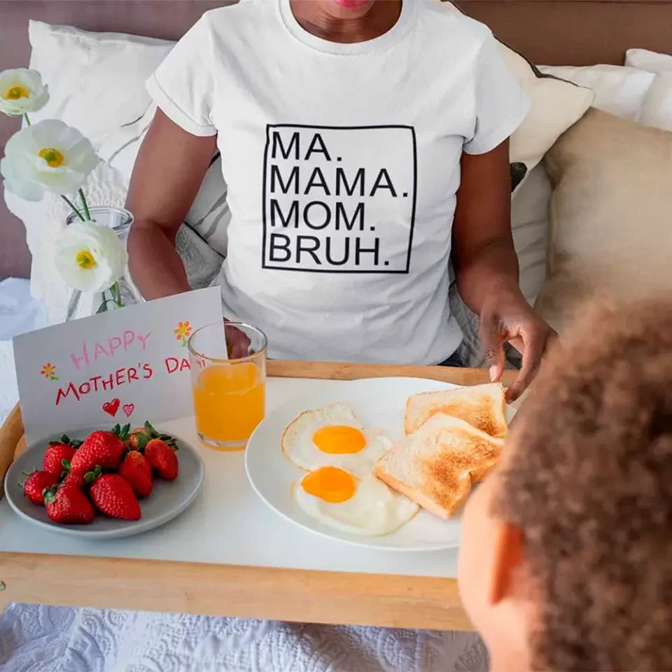 Person wearing a white t-shirt with 'MA. MAMA. MOM. BRUH.' text, serving breakfast to another person.
