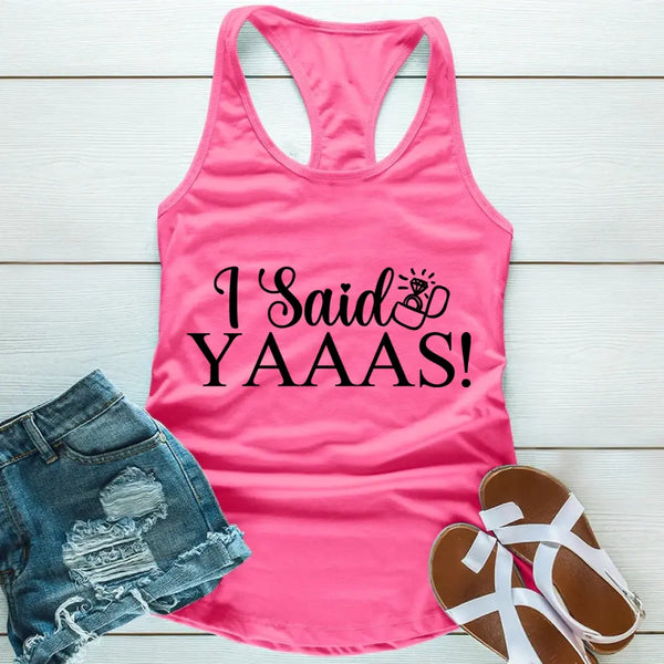 A pink racerback tank top with bold black print reading “I Said Yaaaas!” laid flat on a light