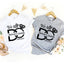 White and gray t-shirts with 'We Still DO' design on hangers with decorative items.