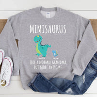 Black t-shirt with a colorful dinosaur design and text 'MIMISARUS like a normal grandma, but more awesome' along with three names: Camilla, Jason, and Mike. 