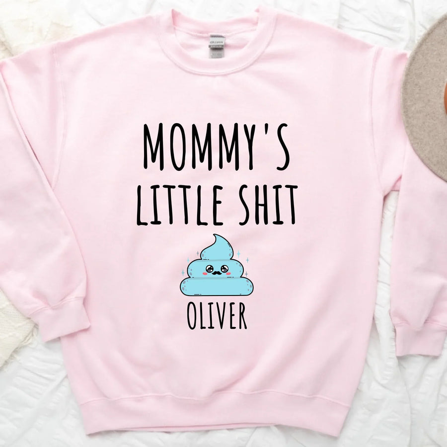 A white t-shirt with the text 'MOMMY'S LITTLE SHIT' printed on the front, above a cartoon graphic of a cloud with the name 'Oliver' added below the graphic.
