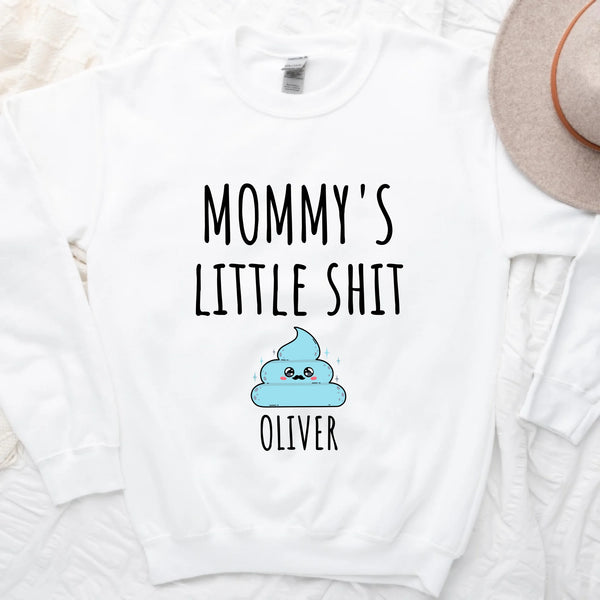 A white t-shirt with the text 'MOMMY'S LITTLE SHIT' printed on the front, above a cartoon graphic of a cloud with the name 'Oliver' added below the graphic.