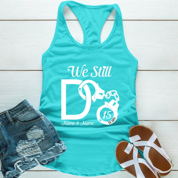 Turquoise tank top with 'We Still Do' design, denim shorts, and sandals on a wooden surface