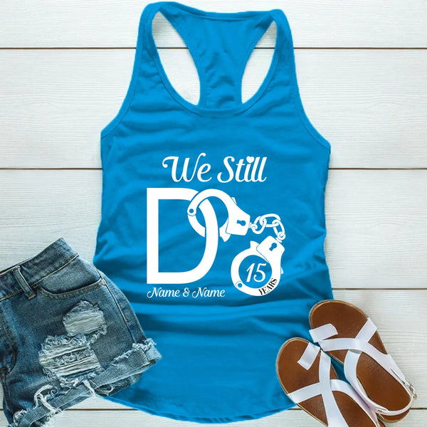 Blue tank top with 'We Still' design on a wooden surface with shorts and sandals.