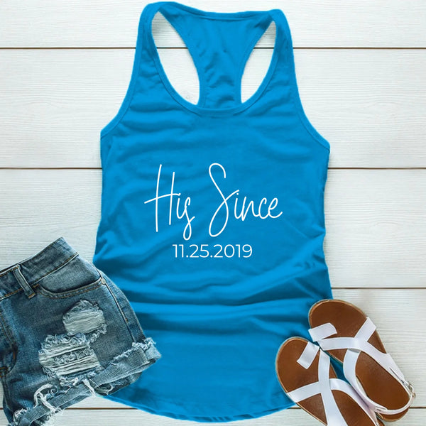 Blue tank top with 'Hers Since 11.25.2019' text, paired with denim shorts and sandals on a wooden surface.