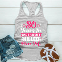 Gray tank top with pink text, denim shorts, and sandals on a light wooden surface