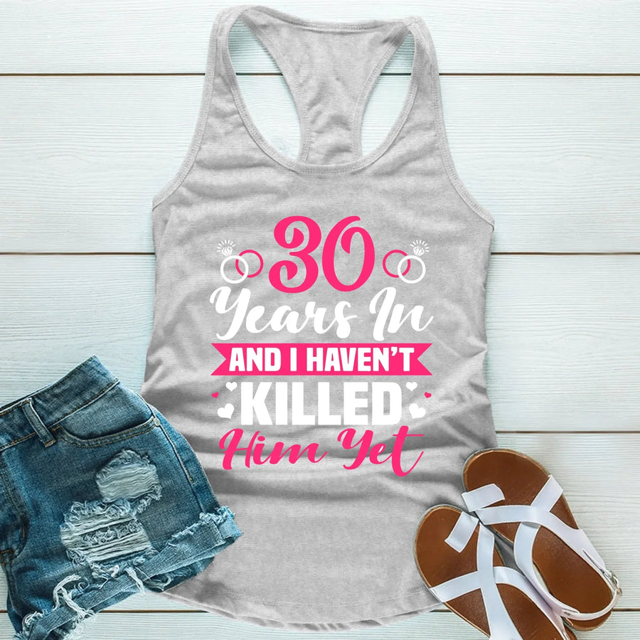 Gray tank top with pink text, denim shorts, and sandals on a light wooden surface