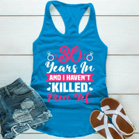 Blue tank top with humorous text, paired with denim shorts and sandals on a wooden surface.