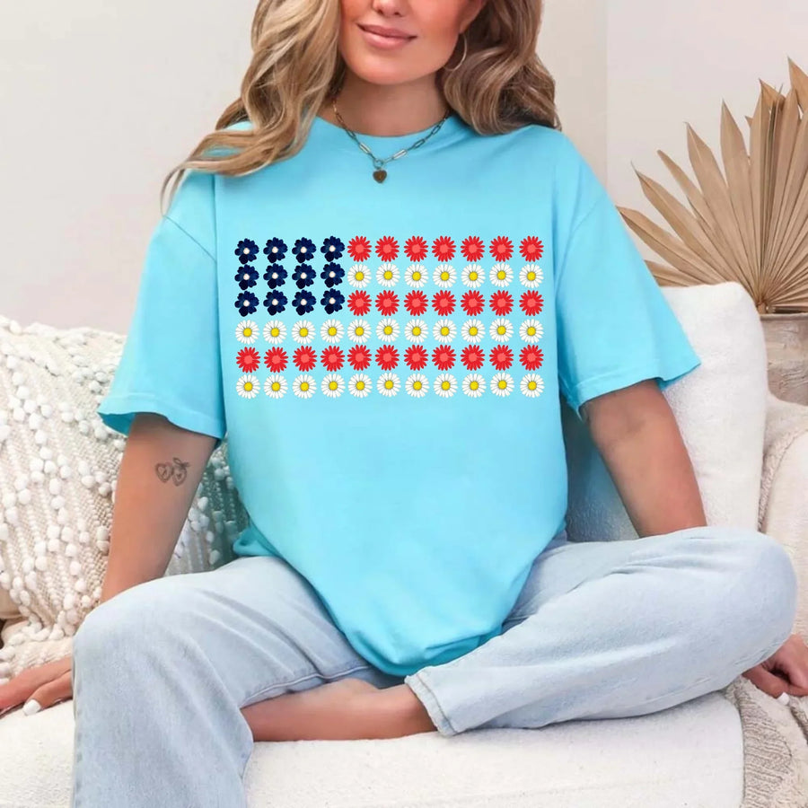 Woman wearing light blue t-shirt with American flag made of red, white, and blue flowers