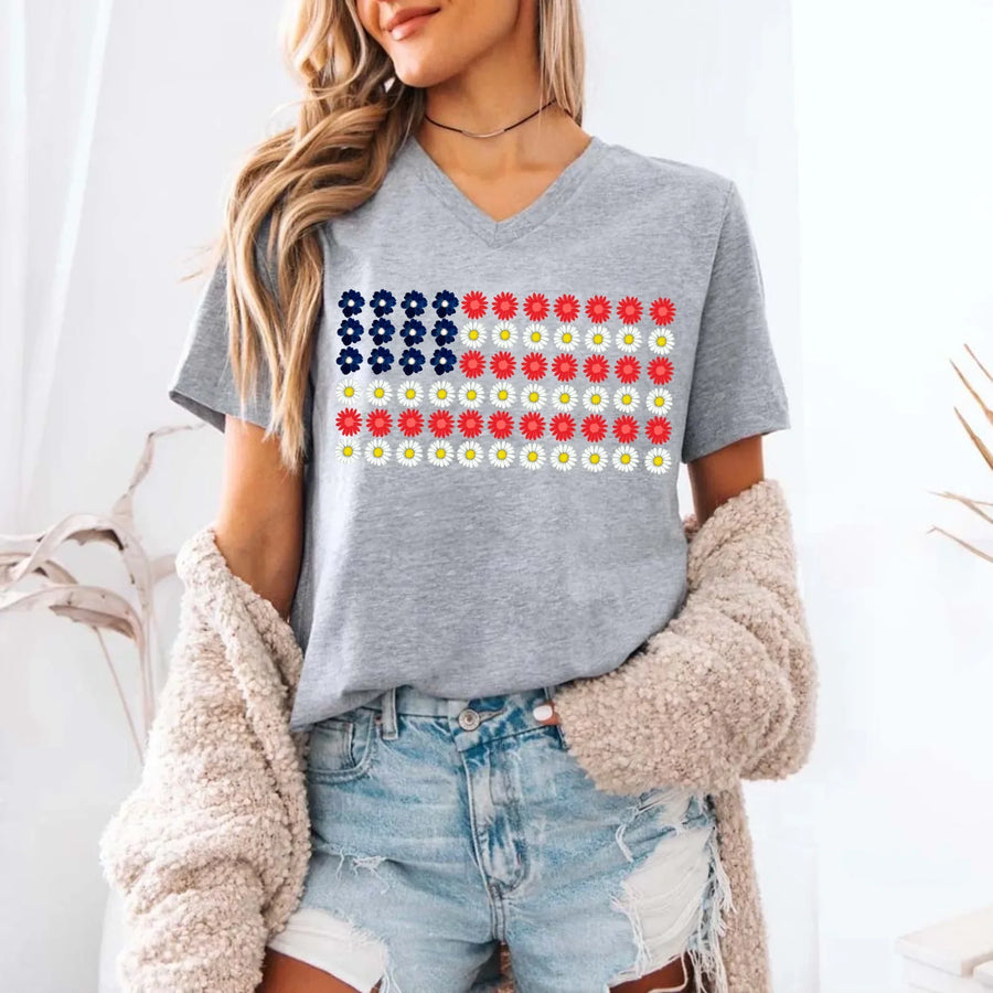 Woman wearing a grey V-neck custom tee with a floral American flag design, paired with denim shorts.