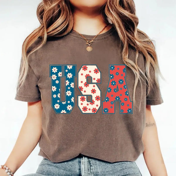 Person wearing a brown t-shirt with 'USA' design featuring flowers.