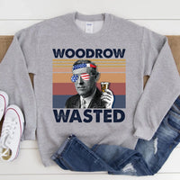 Gray sweatshirt with 'Woodrow Wasted' graphic design on a wooden surface.