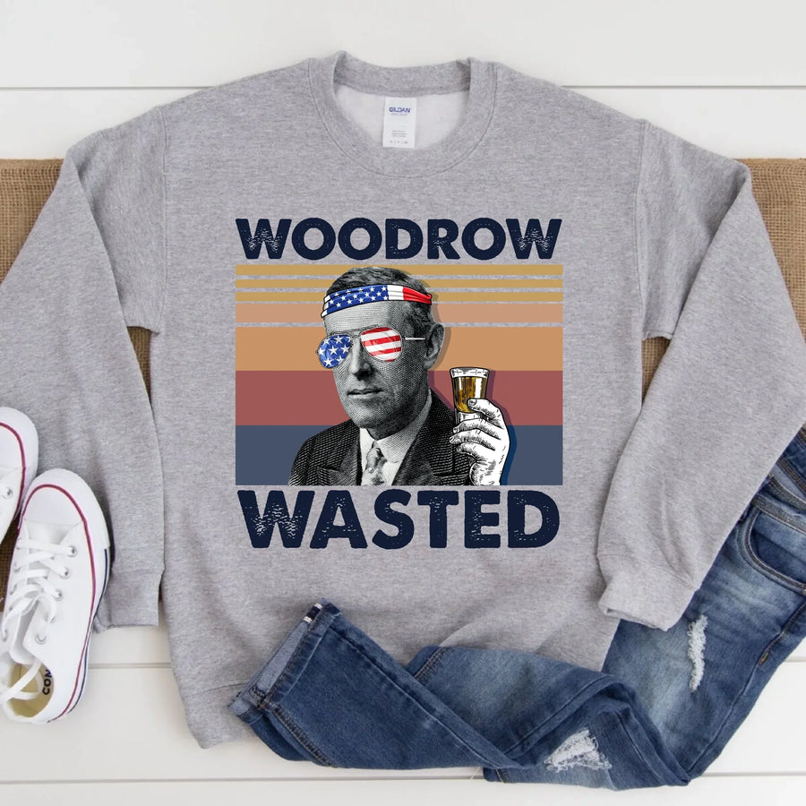 Gray sweatshirt with 'Woodrow Wasted' graphic design on a wooden surface.