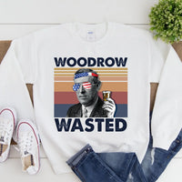 White sweatshirt with graphic design featuring a person holding a drink, sunglasses, and text 'WOODROW WASTED' on a white background.