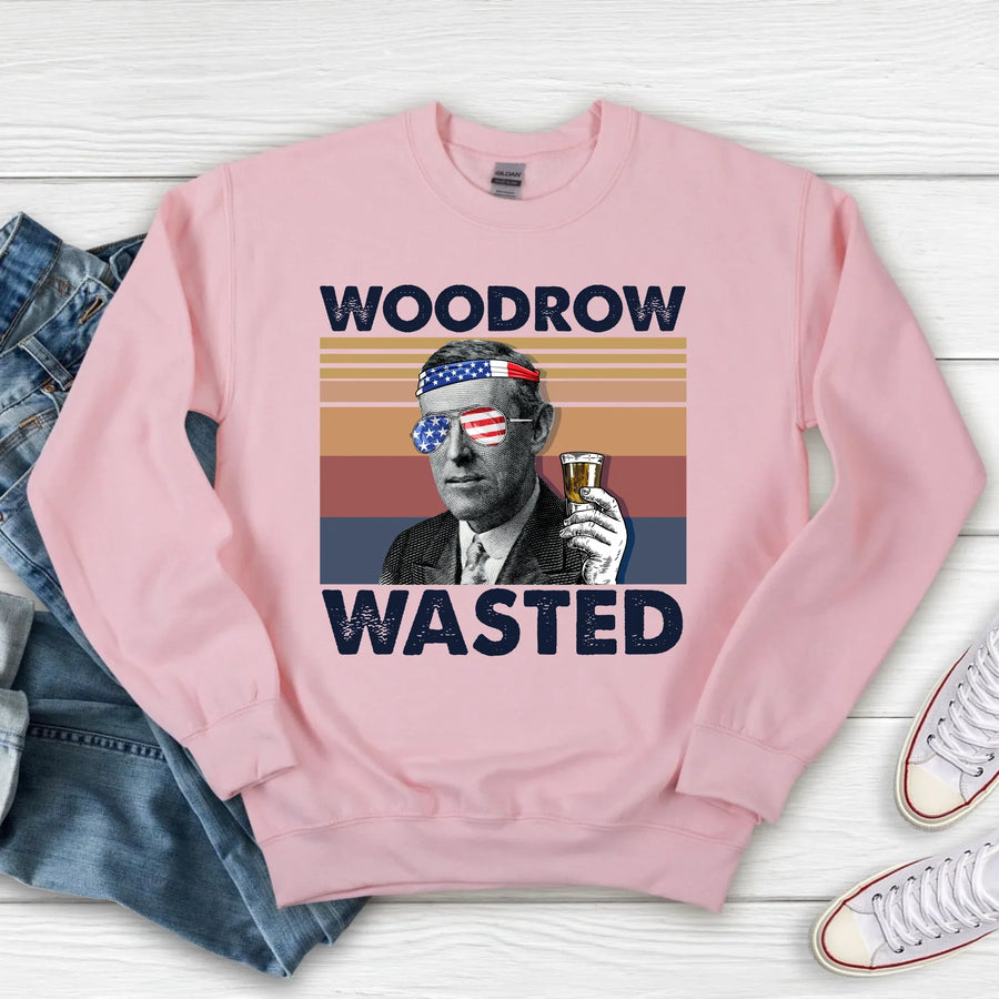 Pink sweatshirt with graphic design and text on a wooden surface with jeans and shoes.