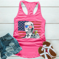 Pink tank top with graphic design of a person holding a drink, American flag, and denim shorts on a wooden surface.