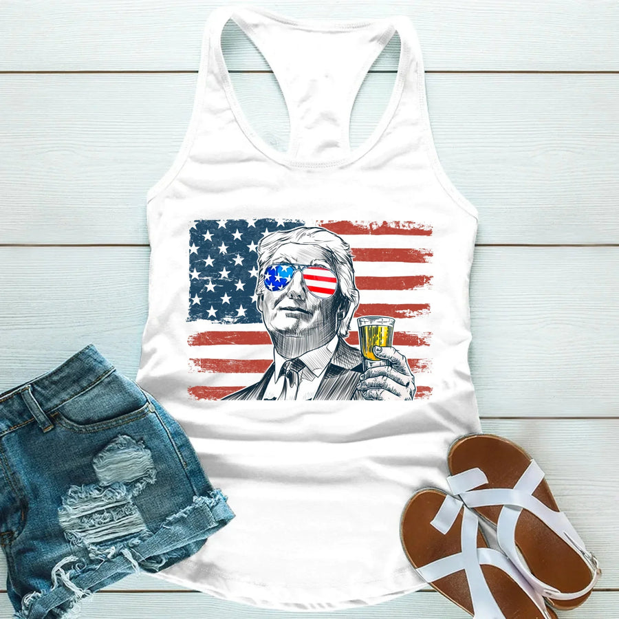 White tank top with American flag and portrait design, paired with denim shorts and sandals on a light wooden surface.