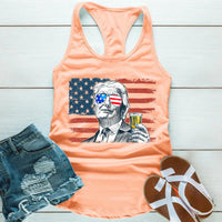Peach tank top with graphic design, denim shorts, and sandals on a wooden surface