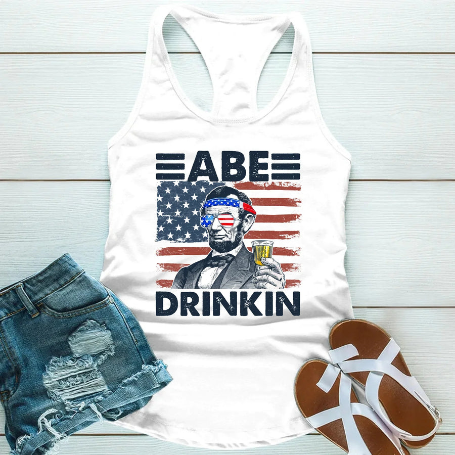 White tank top with American flag graphic and Abraham Lincoln holding a drink, patriotic summer tee