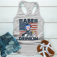 Gray tank top with American flag and Abraham Lincoln graphic, text says Abe Drinkin, paired with denim shorts and sandals.