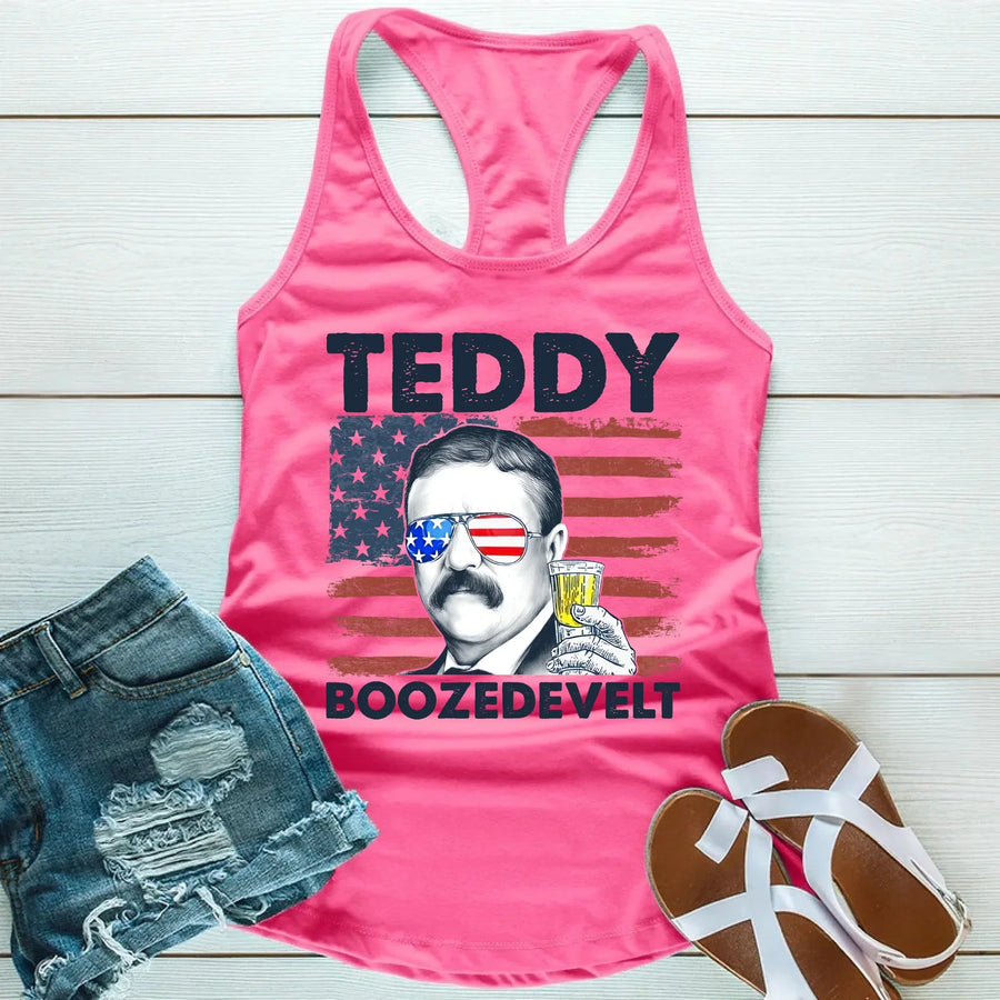 Pink tank top with a graphic of Teddy Roosevelt and text, paired with denim shorts and sandals on a wooden surface.