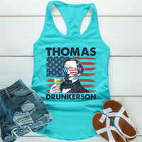 Turquoise tank top with graphic design and text, paired with denim shorts and sandals on a light wooden surface.