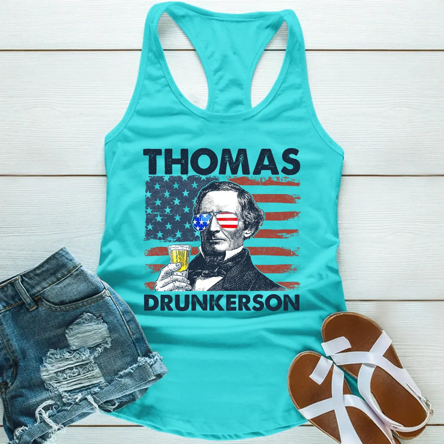 Turquoise tank top with graphic design and text, paired with denim shorts and sandals on a light wooden surface.