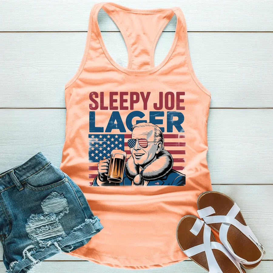 Peach tank top with 'Sleepy Joe Lager' graphic, denim shorts, and sandals on a wooden surface