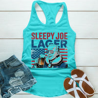 Turquoise tank top with 'Sleepy Joe Lager' graphic on a wooden surface with denim shorts and sandals.