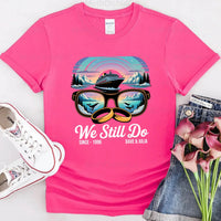Pink custom t-shirt with cruise ship, sunglasses, rings, mountains, and 'We Still Do' text design