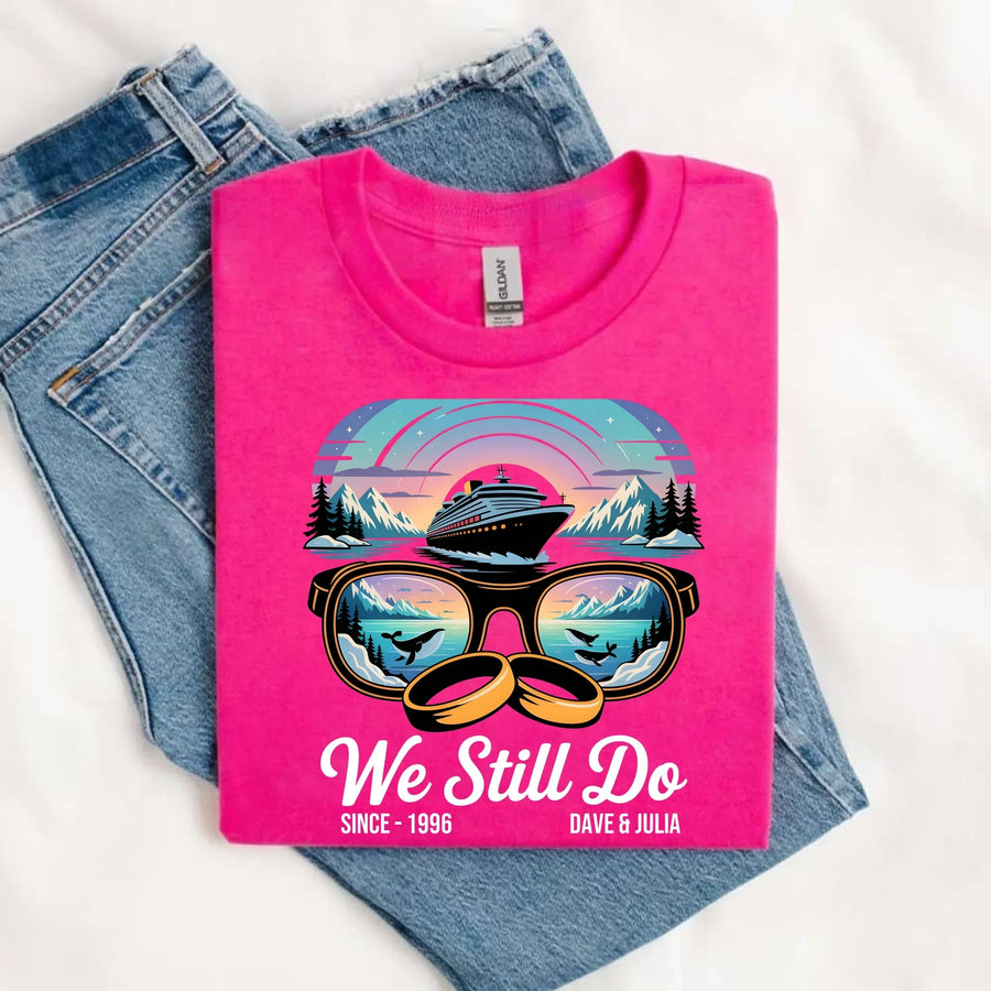 Pink custom tee with cruise ship, sunglasses, mountains, whales, wedding rings and 'We Still Do' text.