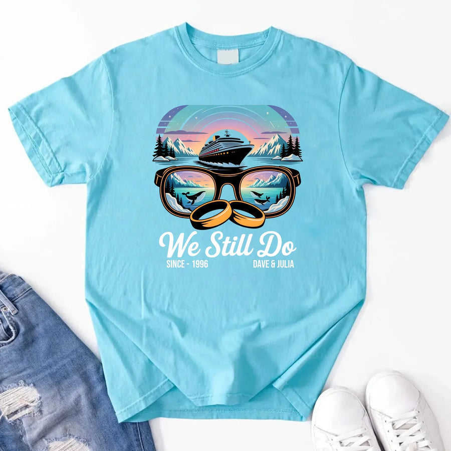 Light blue custom tee with cruise ship, sunglasses, mountains, wedding rings, and 'We Still Do' text