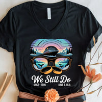 Black custom tee with colorful cruise ship, mountain, and whale graphic, 'We Still Do' text
